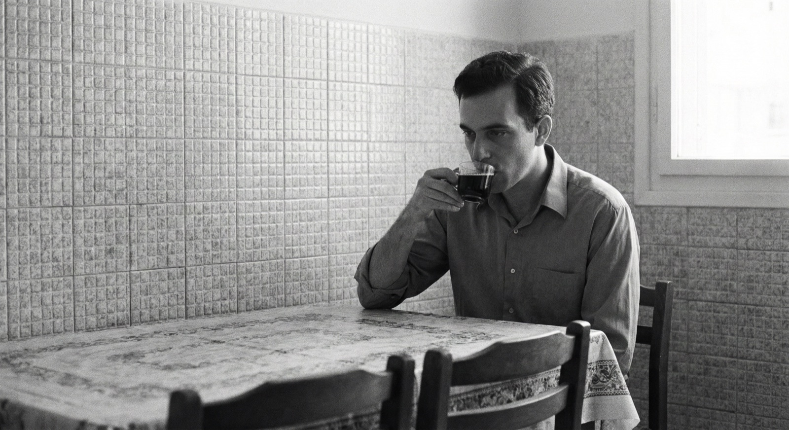 Michael sipping black coffee at the kitchen table, tiled wall behind him
