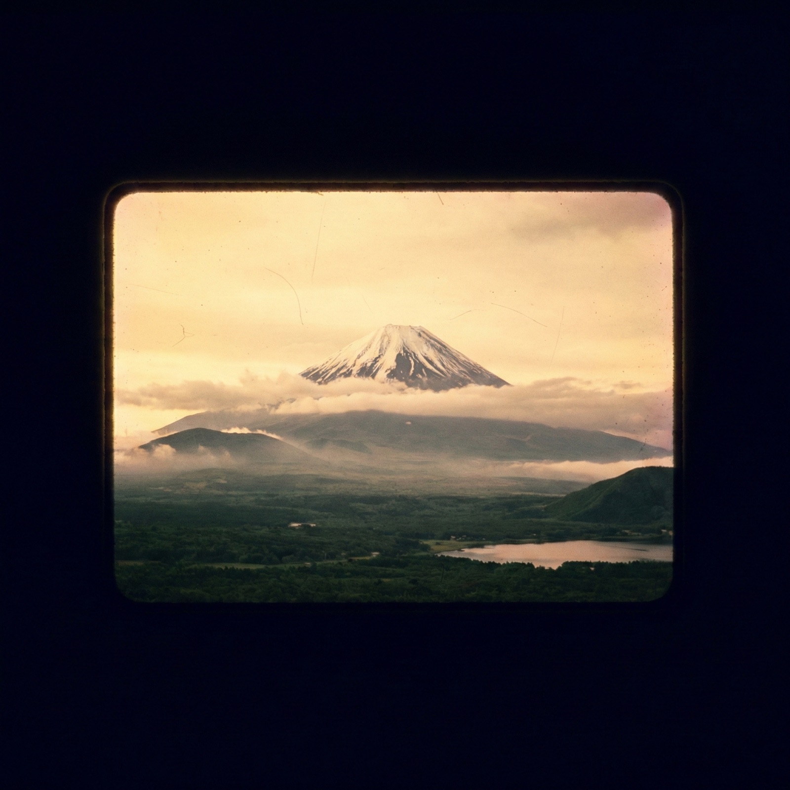 A snow-capped mountain rising above clouds at dusk